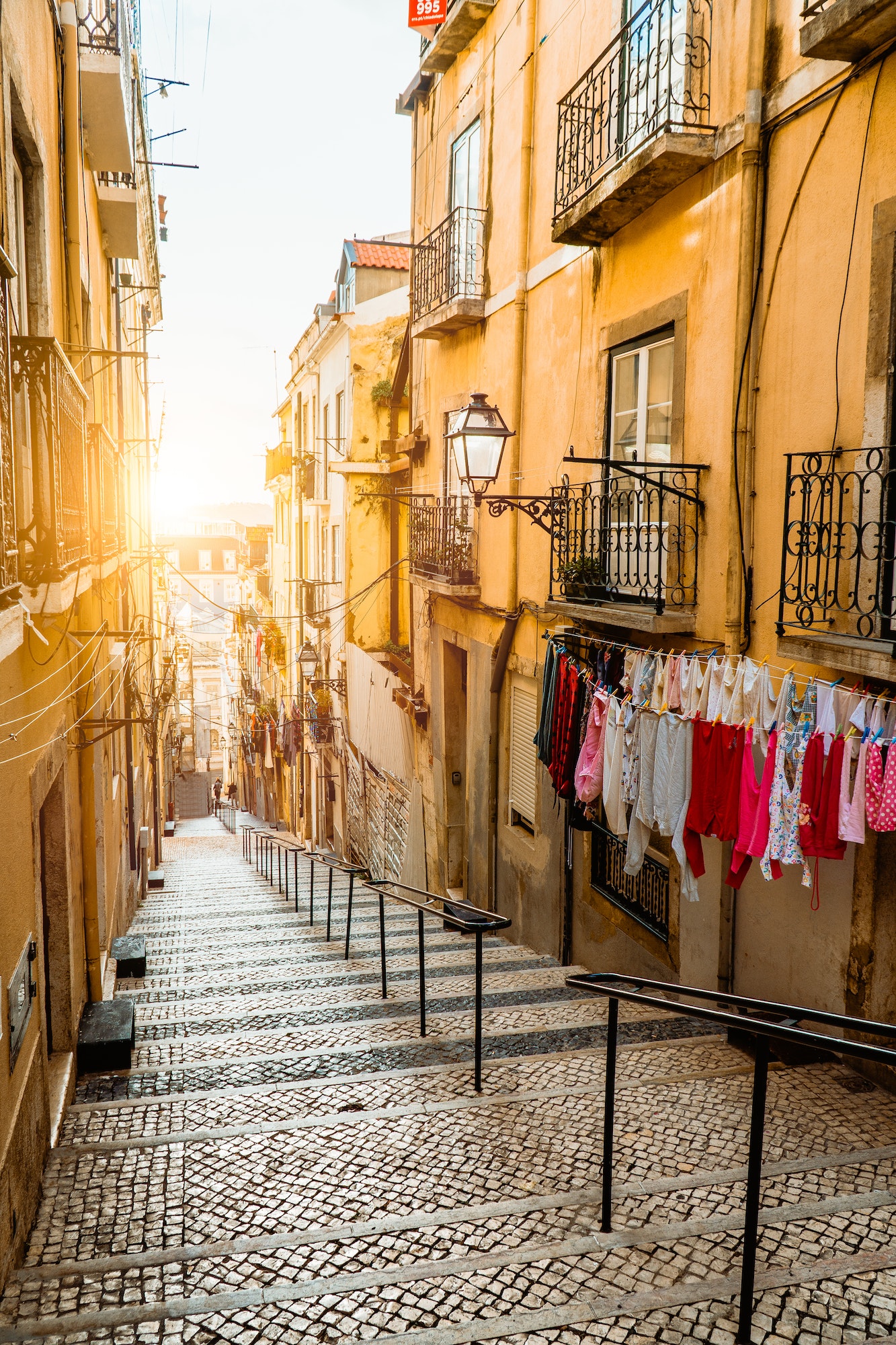 Staircase in the cobblestone street in Lisbon. Hanging laundry in typical narrow street. Sunset in